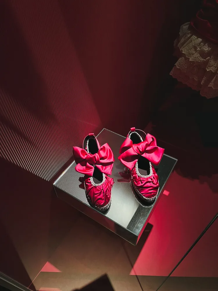Pinke Satinschuhe mit Schleifen in einer Ausstellungsvitrine